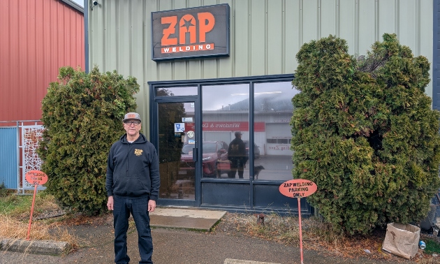 Owner of Zap, Jeff standing outside the Zap building and sign, wearing a baseball cap