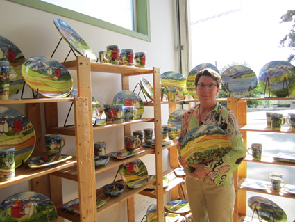 Woman stands among beautiful pottery