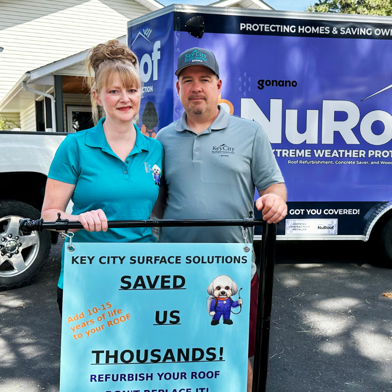 Jeff and Crystal Dyck standing in front of the NuRoof truck holding a sign that says Key City Surface Solutions saved us thousands.