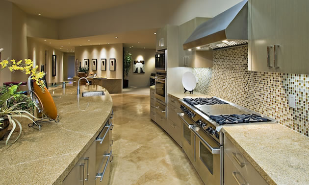 A large modern kitchen with a double stainless steel stove, and granite countertops. 