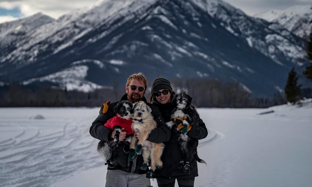 owners with their three small dogs, wearing cute little boots