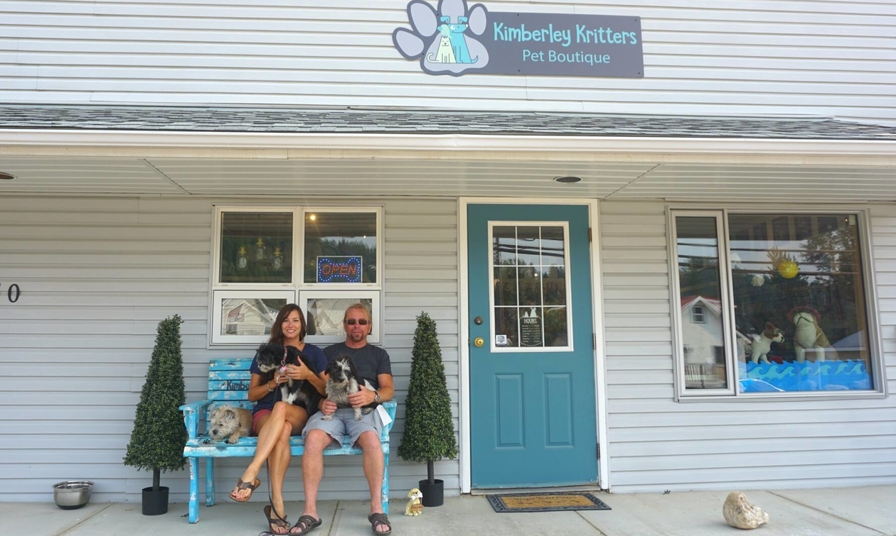 Owners sitting on a bench outside their store with their sweet little dogs