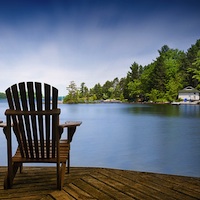 Chairs on a deck overlooking a tranquil lake. 