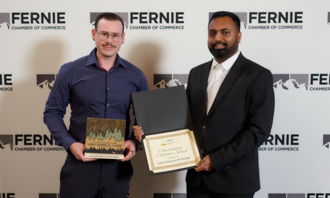 Cavan accepting the 2025 Fernie Business Excellence Award for Outstanding Customer Service from another fellow on stage