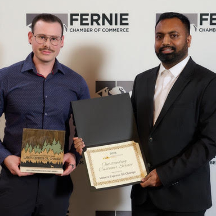 Cavan accepting the 2025 Fernie Business Excellence Award for Outstanding Customer Service from another fellow on stage