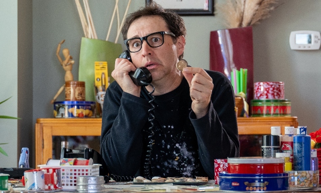 A man with glasses holding a button and dialing the phone