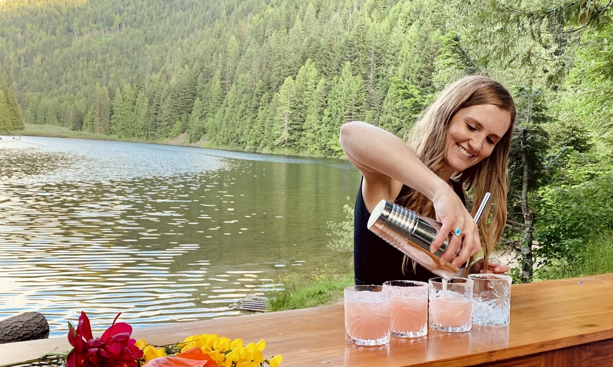 owner of Vintage Pour Mobile Bar pouring a drink with the trees and lake in background