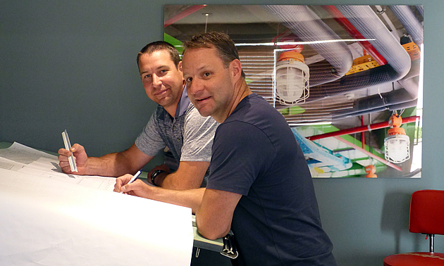 The new owners of M&K standing at a drawing board.