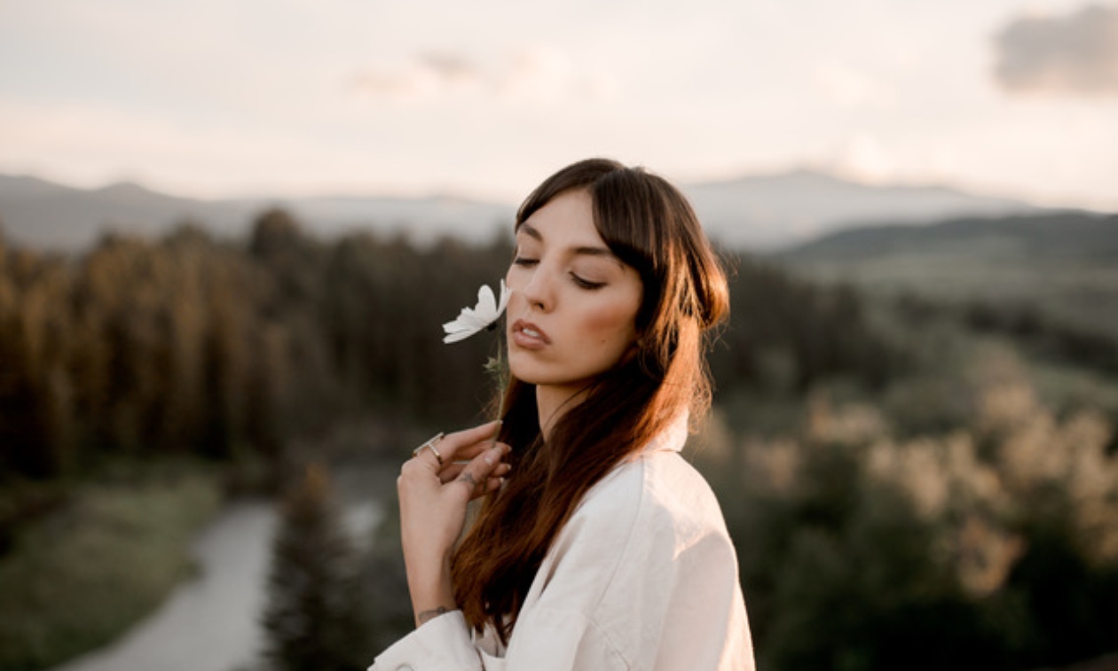 Desiree smelling a white flower wearing a white dress