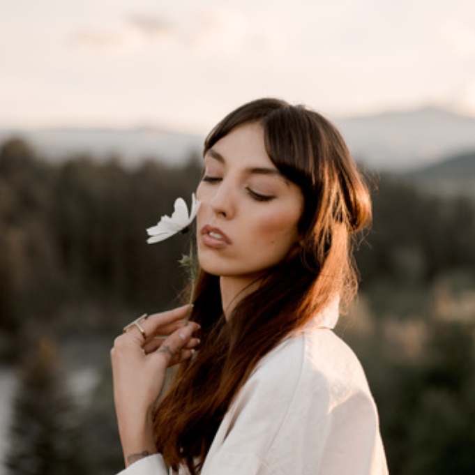 Desiree smelling a white flower wearing a white dress