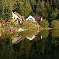 Home near Nelson reflecting in the water of Kootenay Lake.