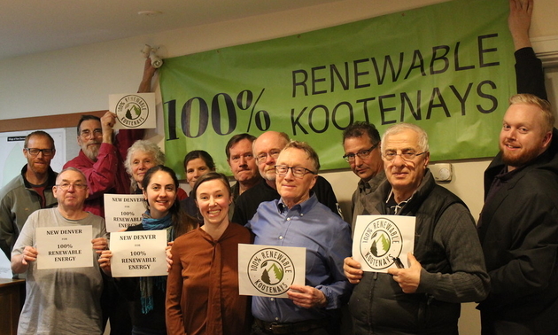 A group of New Denver citizens hold up signs in support of the 100% Renewable Kootenays campaign.