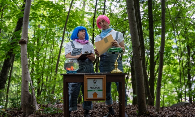 Two actors wearing pink and blue wigs in the forest