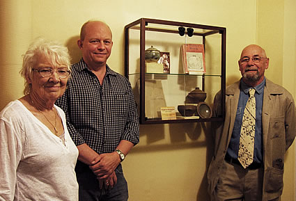 Photo of three people standing beside pottery