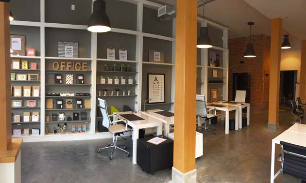 The interior of The Office - Rossland, with white desks and large shelving units, walls are painted grey. 