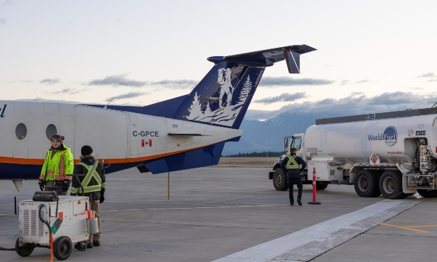 plane on a runway with people on the tarmac