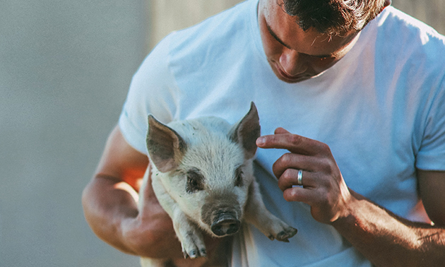 Kieran Poznikoff holding a piglet. 