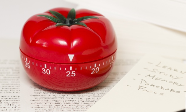 A Pomodoro timer sitting on a paper with writing on it. 