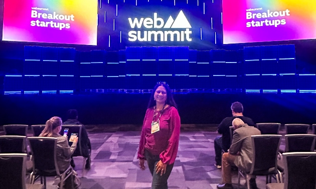 Priya standing on a stage that says Web Summit