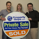 two men and a woman hold up a large round sign for PropertyGuys.com that says Private Sale: Sold