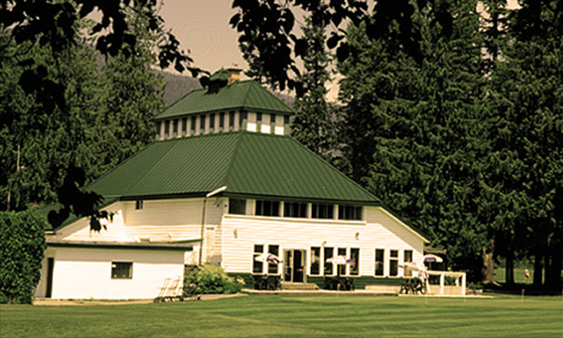 The Revelstoke Golf course clubhouse, a white building with sloping dark green roof. 