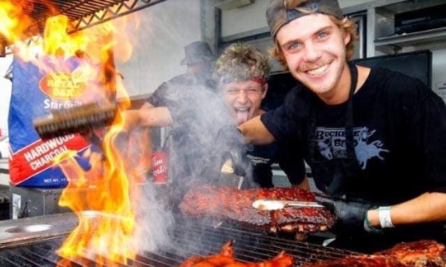 Two young men cooking ribs on a BBQ