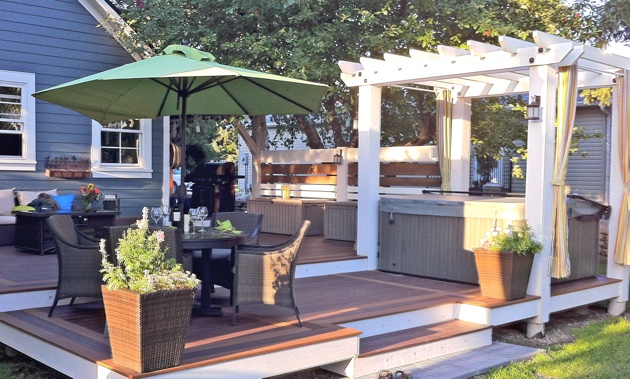 A deck by Rigby Built Construction, complete with a pergola, hot tub, and dining and living areas.