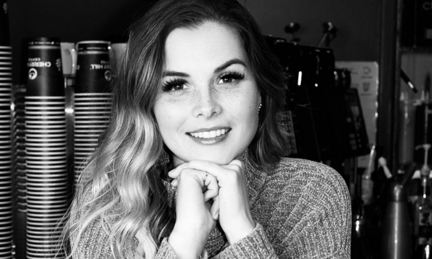 Black and white photo of Robyn Kalnins smiling into the camera with her hands folded