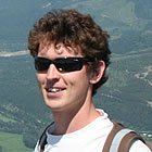 A man standing at a distance from Fernie with a backpack and sun-glasses.