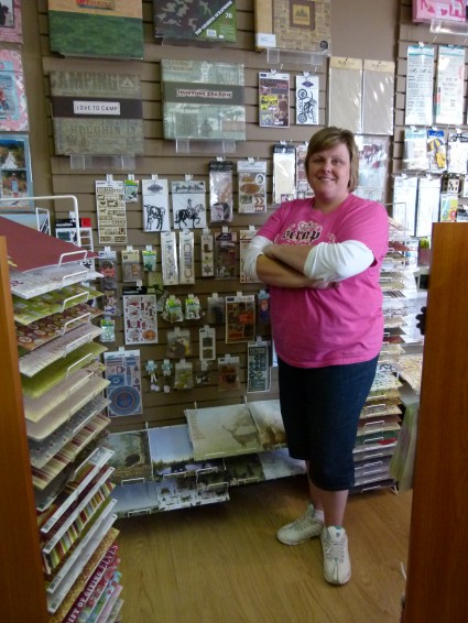 Woman stands in front of scrap-booking items displayed in a store