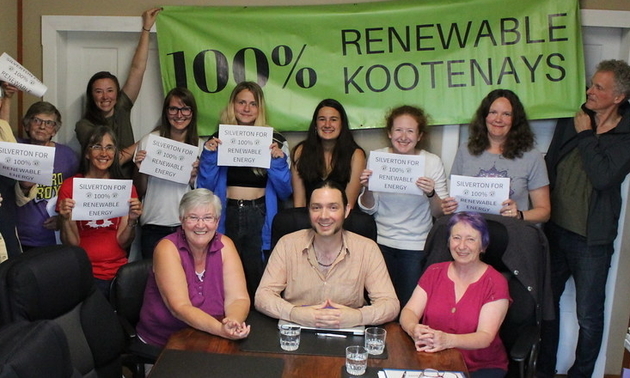 A group of Silverton citizens hold up signs in support of the 100% Renewable Kootenays campaign.