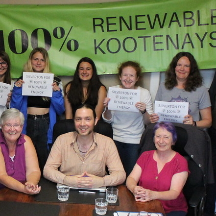 A group of Silverton citizens hold up signs in support of the 100% Renewable Kootenays campaign.