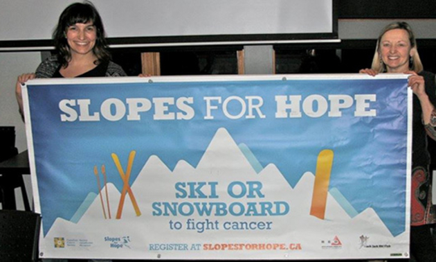 Two ladies holding up a Slopes for Hope banner