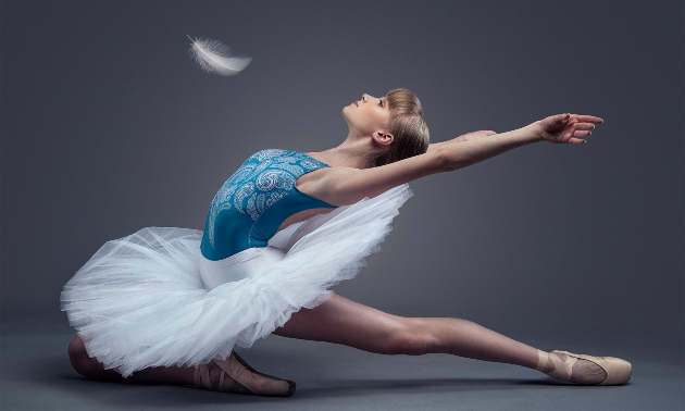 Ballet dancer bending backward with a feather falling above her