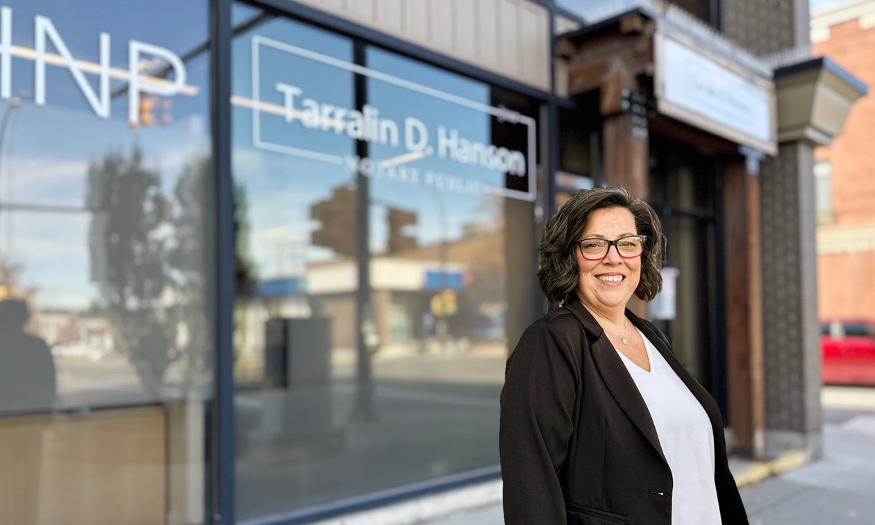 Tarralin D. Hanson, wearing a dark blazer and white blouse standing in front of her business