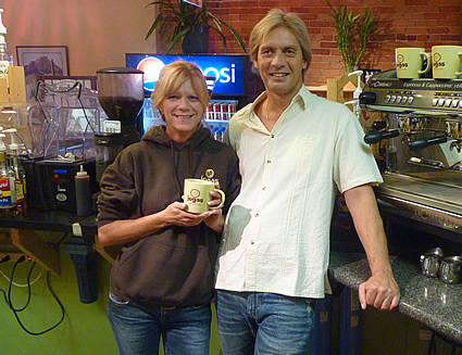 A man and a woman standing together holding a mug of coffee