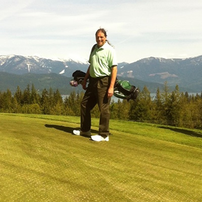Rick Frye, owner of The Golf Doctor, on golf course with mountains in the background. 