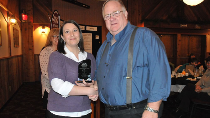 Nicole Pipes from Community Futures of Greater Trail (sponsor) presenting the Business of the Year Award trophy to Valley Firearms owner John Urquart.
