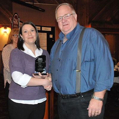 Nicole Pipes from Community Futures of Greater Trail (sponsor) presenting the Business of the Year Award trophy to Valley Firearms owner John Urquart.
