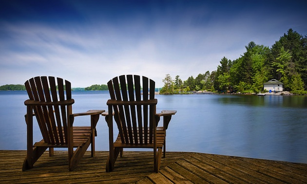 Chairs on a deck overlooking a tranquil lake. 