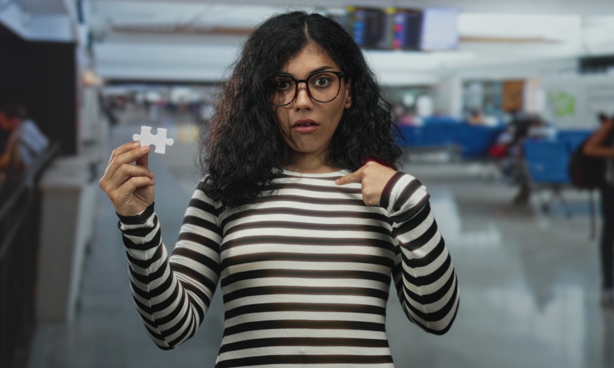 Woman holding a puzzle piece, wearing a black and white striped shirt.