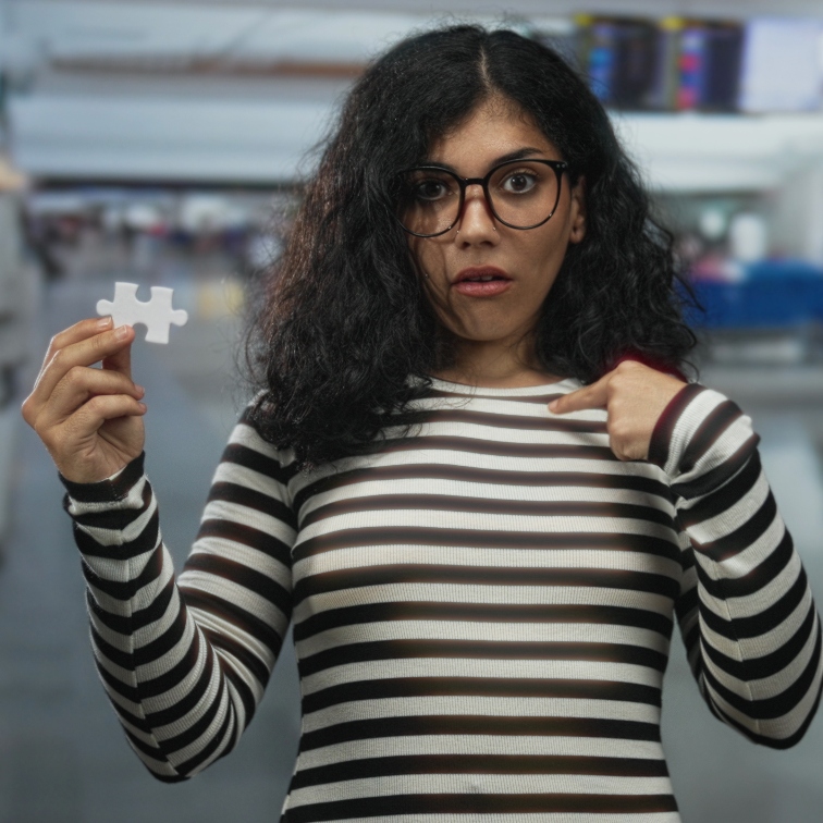 Woman holding a puzzle piece, wearing a black and white striped shirt.