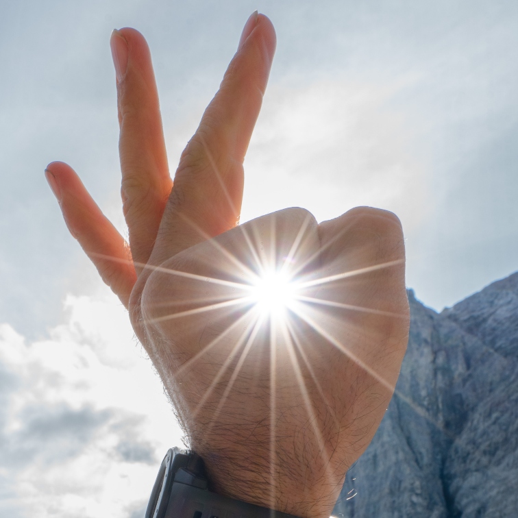 person's hand making an OK sign around the sun
