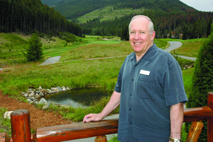 Man standing with mountain golf course in background