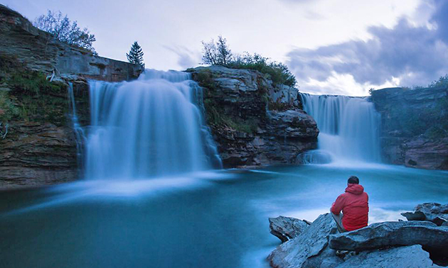 Kyle Hamilton sitting beside picturesque waterfall. 