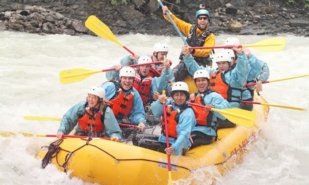 A group of whitewater rafters in a yellow raft. 