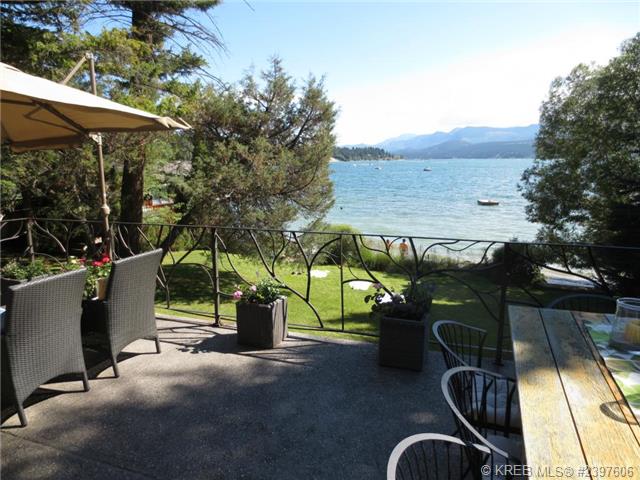 An image of the outdoor back deck with a large table for entertaining and a view of the lake. 