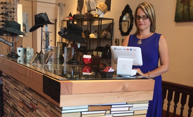 Owner Zabrina Nelson of Revival Boutique stands behind a desk made of over 1,000 recycled books glued together.